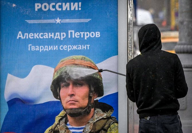 AFP/„Scanpix“ nuotr./Maskvoje valomas propagandinis plakatas su kariu ir užrašu „Šlovė Rusijos didvyriams“