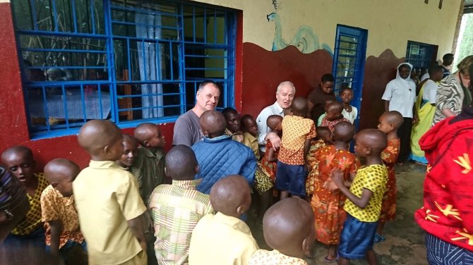 Kelionių organizatoriaus „GRŪDA“ nuotr./„GRŪDOS“ keliautojas R. Vilkas su stovyklos vaikais ir H. Šulcu, Ruanda