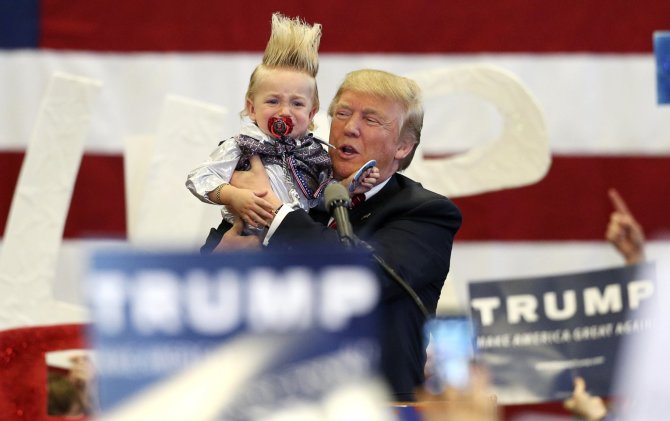 „Reuters“/„Scanpix“ nuotr./Donaldas Trumpas laiko vaiką