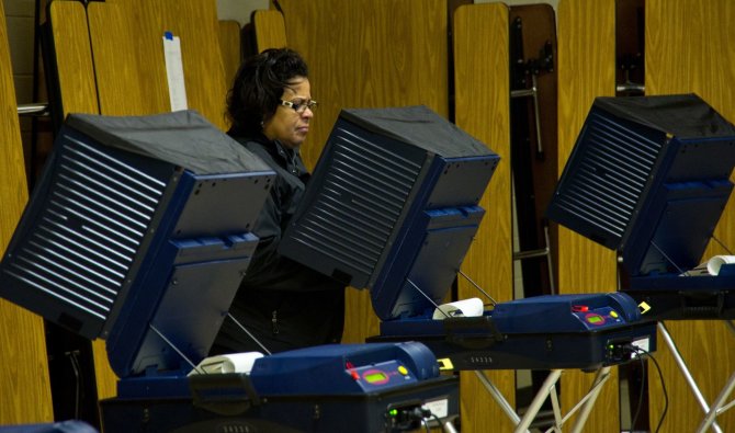 AFP/„Scanpix“ nuotr./Amerikietė atiduoda balsą balsavimo mašinoje 2012 metų prezidento rinkimuose