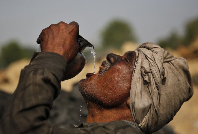 „Scanpix“/AP nuotr./Darbininkas Indijoje geria vandenį