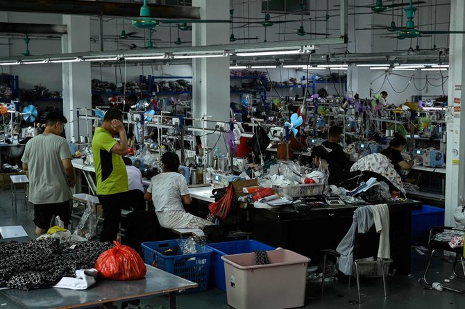AFP/„Scanpix“ nuotr./2022 m. liepos 18 d. Kinijos Guangdžou mieste esanti drabužių gamykla, kuri tiekia drabužius greitosios mados elektroninės prekybos bendrovei „Shein“.