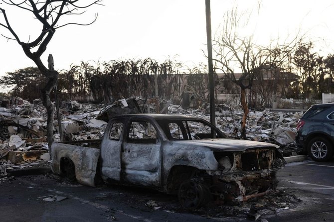 AFP/„Scanpix“ nuotr./Po gaisro sudegęs automobilis guli ant apdegusio daugiabučio kiemo važiuojamosios dalies