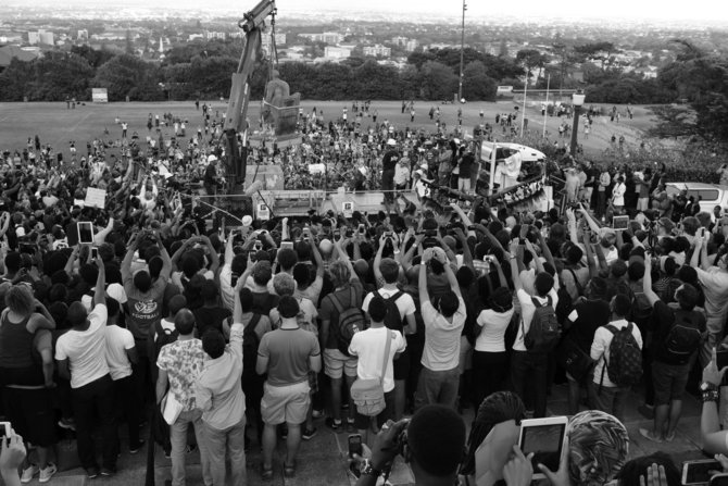 D.Goldblatto palikimo fondo ir Goodman galerijos nuosavybė/David Goldblatt. Kolonialistas Cecilis Johnas Rhodesas nuverčiamas nuo sosto po to, kai per studentų protestą „Rhodesas turi kristi“ jo statula buvo apmėtyta žmonių išmatomis. Universitetas sutiko su studentų reikalavimu statulą nugriauti. Keiptauno universitetas. 2015