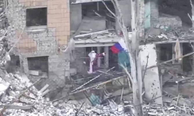 Imago / Scanpix nuotr./Seniu Šalčiu persirengę Rusijos karys su vėliava Myrnohrado griuvėsiuose. Šį kadrą iš vaizdo įrašo išplatino Rusijos gynybos ministerija.