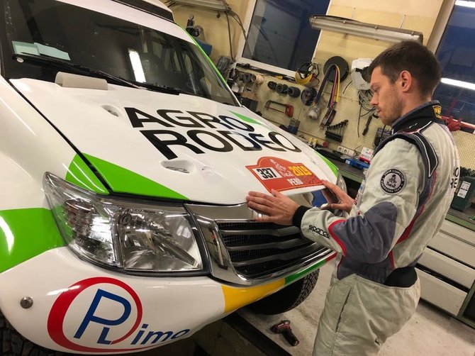 Agrorodeo komandos nuotr./Vaidotas Žala klijuoja ant Agrorodeo komandos automobilio startinį Dakaro 2019 numerį