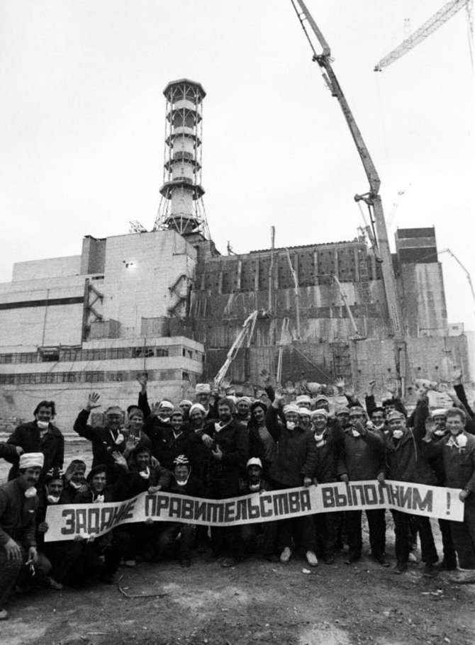 „Reuters“/„Scanpix“ nuotr./Černobylio katastrofos likviduotojai. Ant plakato užrašas: „Vyriausybės užduotį įvykdysime!“