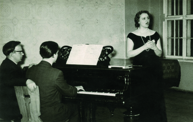 Nacionalinės bibliotekos ir Klovų šeimos archyvo nuotr./Jonas Mackonis (kairėje), Vytautas Klova ir Liudmila Mackonienė repetuoja Mirtos ariją iš operos „Pilėnai“, 1955.