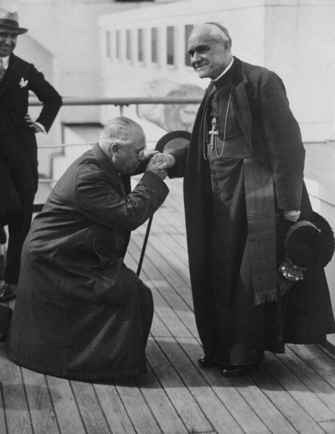Vida Press nuotr./Ispanijos ambasadorius bučiuoja ranką į Čikagą atvykusiam savo tėvynainiui kardinolui, 1926 m.