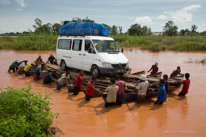 Akvilės Norkutės nuotr./Madagaskare po lietaus patvinus upei nemaža dalis kelio atsidūrė po vandeniu, tad autobusiukas gelbėjamas savadarbiu keltu