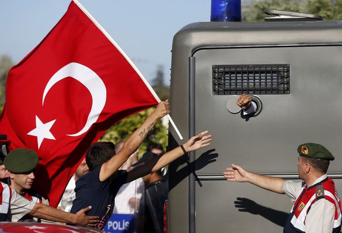 „Reuters“/„Scanpix“ nuotr./Protestuotojas su Turkijos vėliava bėga paskui į teismą vežamą kalinį