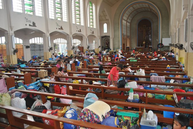 AFP/„Scanpix“ nuotr./Prie Filipinų artėjant taifūnui žmonės apsistojo bažnyčioje