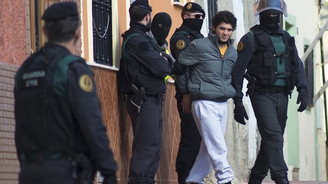 „Reuters“/„Scanpix“ nuotr./Policijos vedamas asmuo, įtariamas verbavimu į islamistų kovotojų grupuotes.