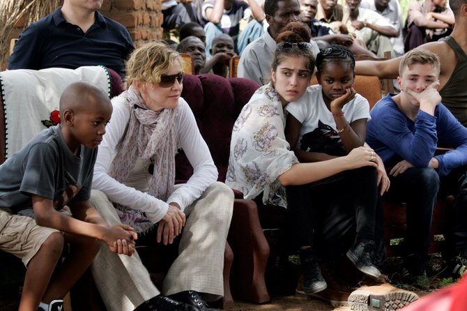 AFP/„Scanpix“ nuotr./Madonna su vaikais (iš kairės) Davidu Banda, Lourdes, Mercy James ir Rocco Malavyje 2013 metais