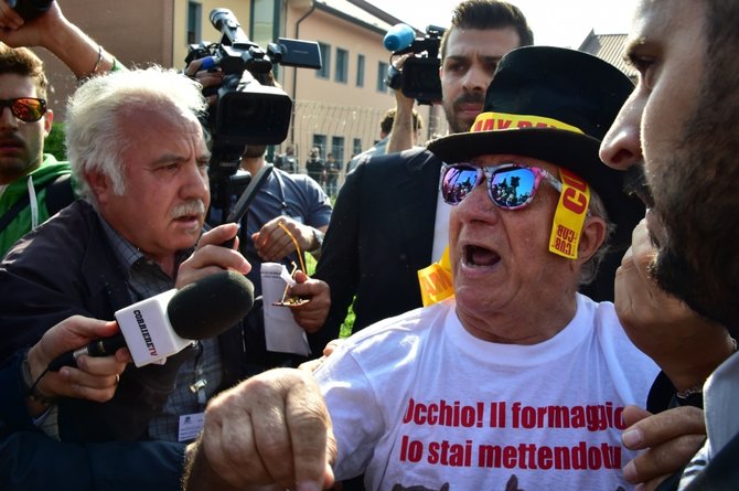 AFP/„Scanpix“ nuotr./Protestuotojas prie ligoninės, kurioje visuomenei naudingą darbą atlieka buvęs Italijos premjeras Silvio Berlusconi