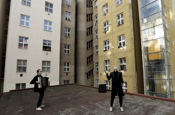 „Scanpix“/AP nuotr./Artistų trupės „ Cirk La Putyka“ nariai linksmina gyventojus daugiabučių namų kvartale. Įvairiose šalyse menininkai rengia koncertus, pasirodymus šalia namų, kurių palikti žmonėms nerekomenduojama. Praha, Čekija.