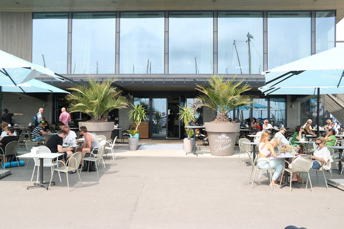 D.Nikitenkos nuotr./Nidos uostelio prieplaukoje - jauki restorano terasa, nuo kurios atsiveria vaizdas į kopas, marias, grakščias jachtas. Ar dera čia nerijai nebūdingos palmės?