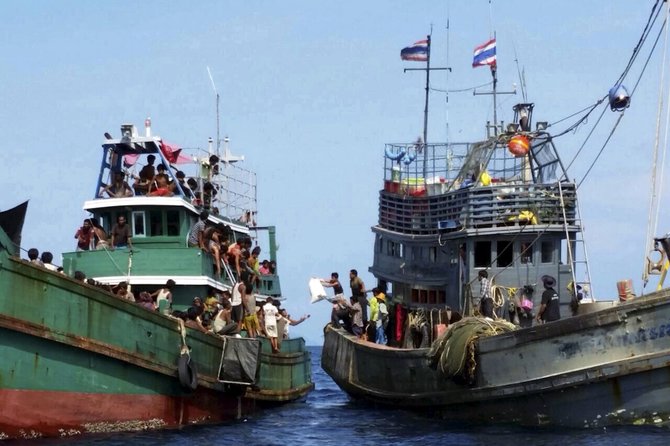 „Reuters“/„Scanpix“ nuotr./Žvejų laivas dalinasi savo maisto atsargomis su dreifuojančiais imigrantais