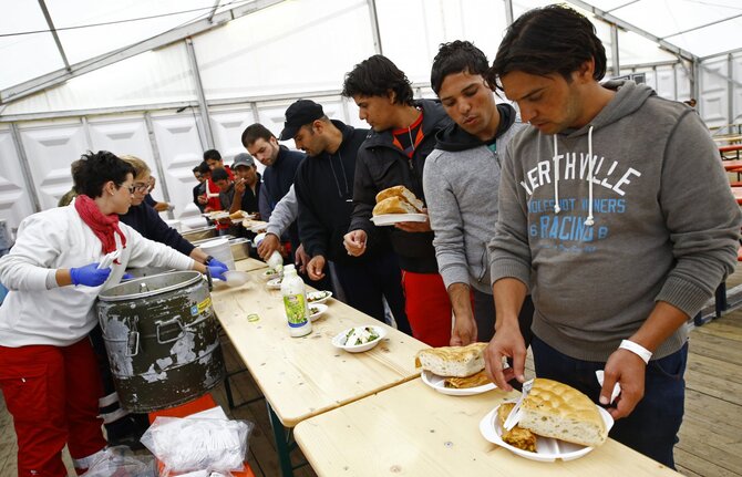 „Reuters“/„Scanpix“ nuotr./Migrantams dalijamas maistas