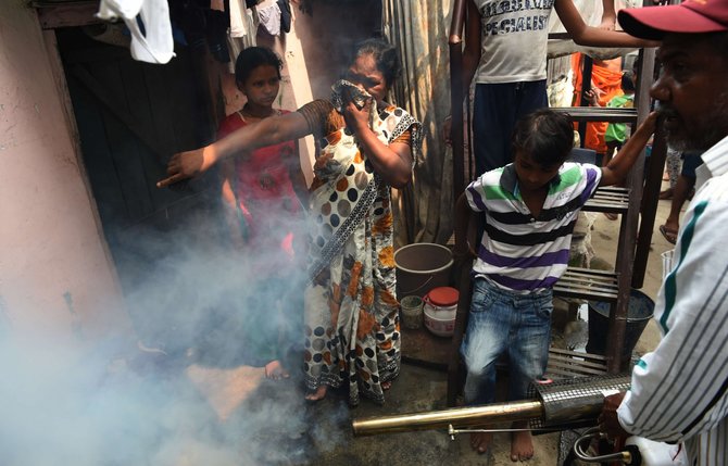 AFP/„Scanpix“ nuotr./Indijos sostinė purškiama priemone nuo uodų, pernešančių Dengės virusą