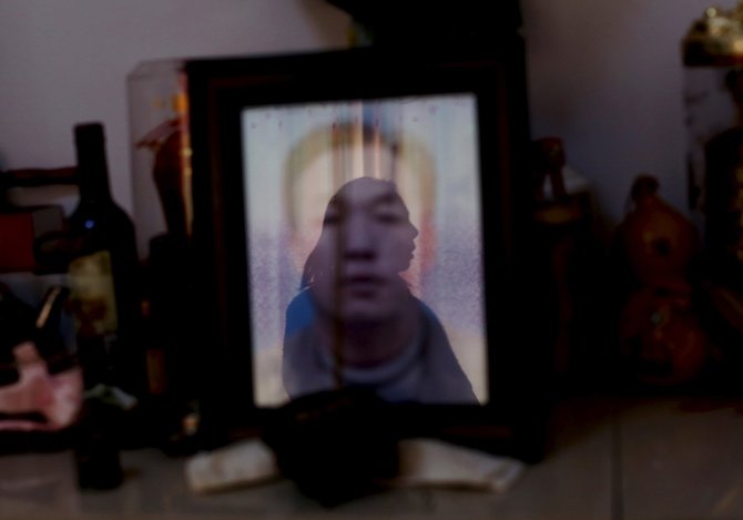„Reuters“/„Scanpix“ nuotr./Cui Wenlan atsispindi ant mirusio sūnaus nuotraukos