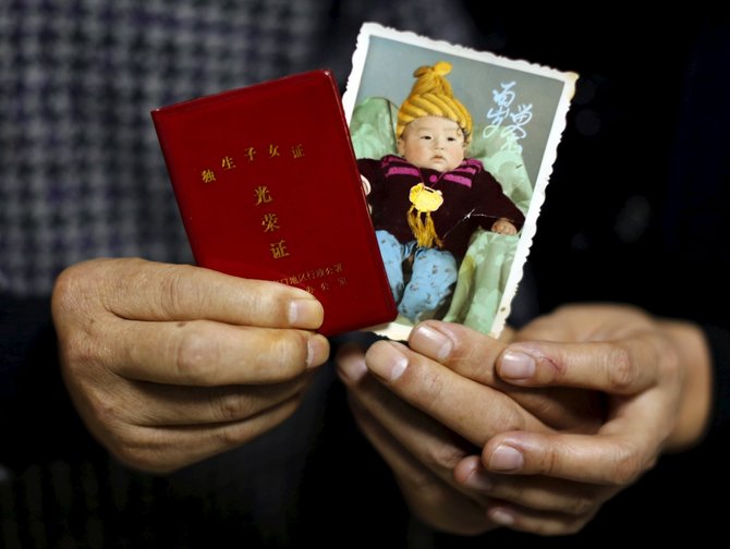 „Reuters“/„Scanpix“ nuotr./Zhang Yinxiu rodo sūnaus nuotrauką su jo garbinguoju vienintelio vaiko sertifikatu