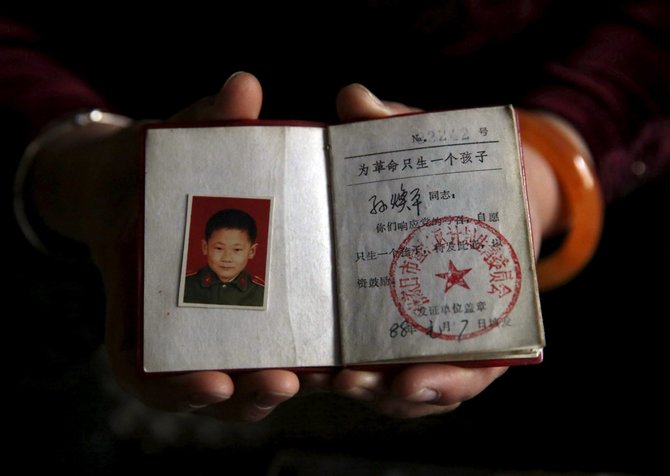 „Reuters“/„Scanpix“ nuotr./Sun Huanping rodo savo sūnaus garbingąjį vienintelio vaiko sertifikatą