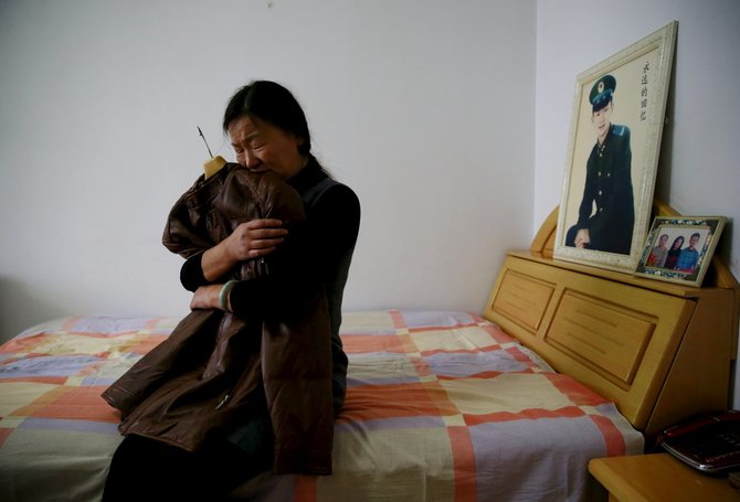 „Reuters“/„Scanpix“ nuotr./Zheng Qing apkabina savo mirusio sūnaus mėgstamiausią striukę