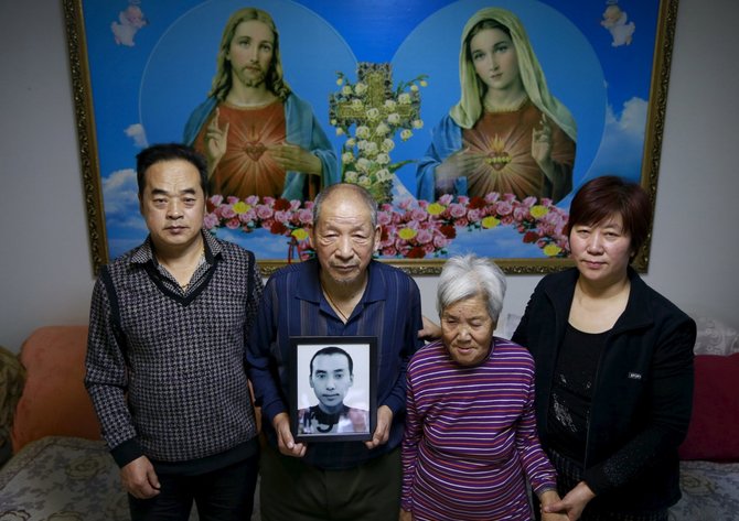 „Reuters“/„Scanpix“ nuotr./Jiangas Weimao'as su žmona Zhang Yinxiu, tarp jų Zhang tėvai, kurie laiko žuvusio sūnaus nuotrauką