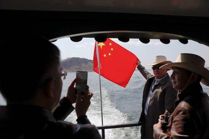 „Reuters“/„Scanpix“ nuotr./Kinų turistai kelte Jaludziango upėje