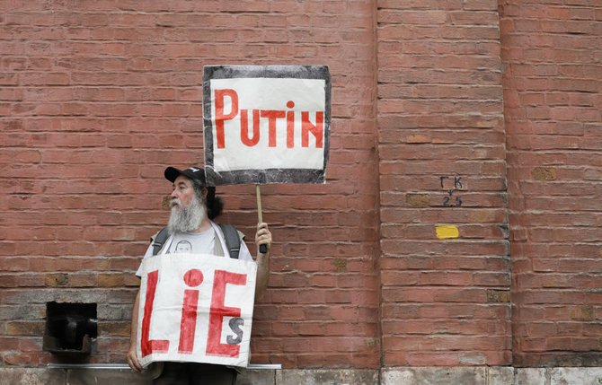 „Reuters“/„Scanpix“ nuotr./Vienišas protestuotojas Maskvoje plakatais anglų kalba skelbia: „Putinas meluoja“