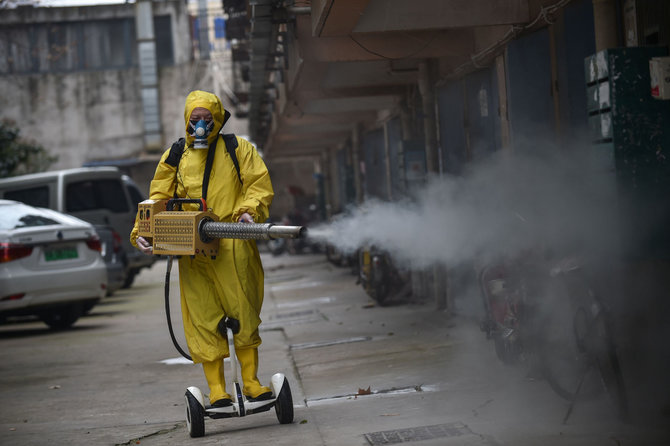 AFP/„Scanpix“ nuotr./Darbininkas purškia dezinfektantą Uhano mieste