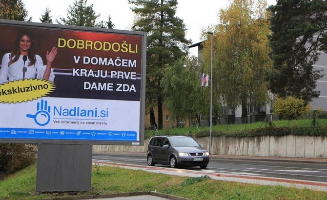 „Facebook“ nuotr./Reklaminis plakatas su M.Trump pasitinka įvažiuojančiuosius į Sevnicą