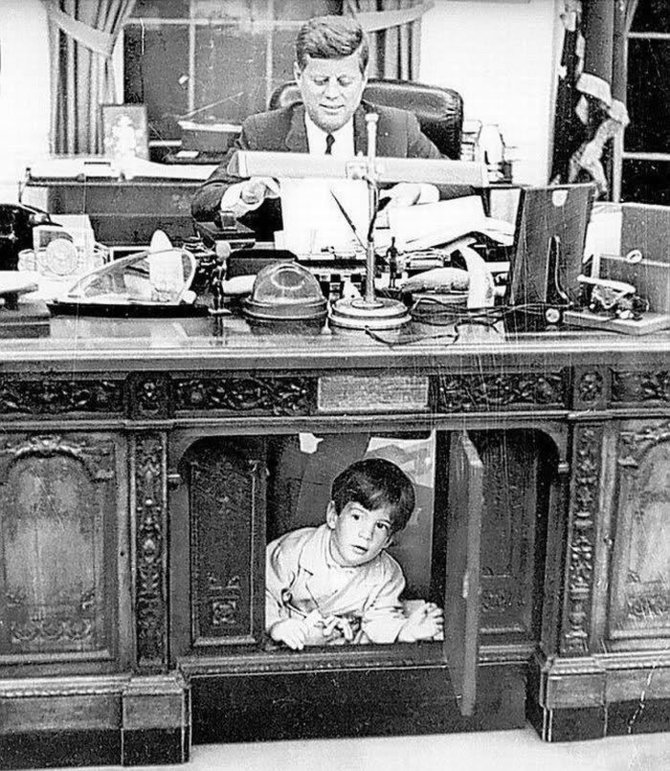 „Facebook“ nuotr./Johno F.Kennedy sūnus Johnas žaidžia po prezidento stalo Baltuosiuose rūmuose.
