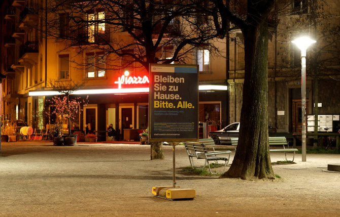 „Reuters“/„Scanpix“ nuotr./Ciurichas per karantiną. Plakatu raginama likti namie.