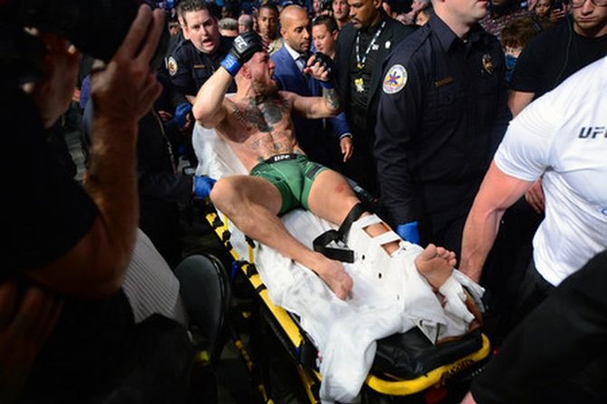 „Scanpix“ nuotr./Conoras McGregoras ir Dustinas Poirier kovos ringe Las Vegase. Dvikova buvo nutraukta, C.McGregorui patyrus čiurnos lūžį.