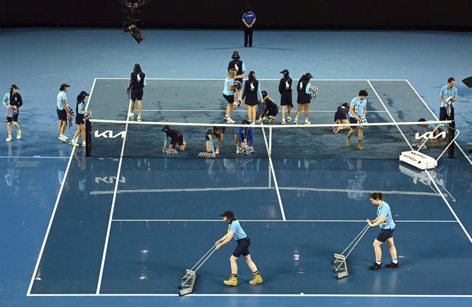 „Scanpix“ nuotr./„Australia Open“ turnyre savanoriams teko rankšluosčiais sausinti aikštę.