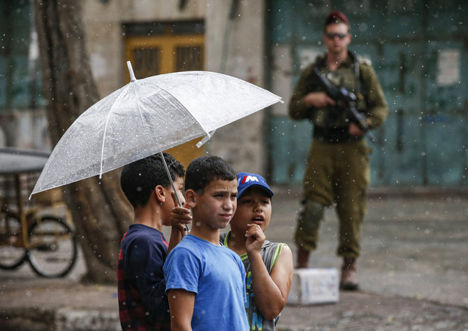 AFP/„Scanpix“ nuotr./Palestiniečių berniukai ir Izraelio karys Hebrone