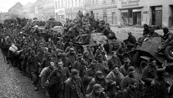 Leidėjų nuotr./Berlyno gatvėmis juda vokiečių karo belaisvių kolona. Į juos nuo šarvuotos technikos žvelgia raudonarmiečiai. 1945 m. balandžio pabaiga.