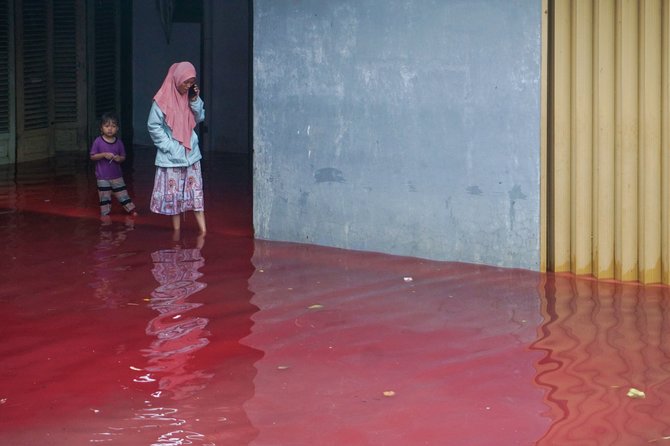 AFP/„Scanpix“ nuotr./Indonezijoje batikos dažai raudonai nudažė potvynio vandenis
