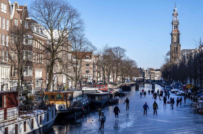 AFP/„Scanpix“ nuotr./Amsterdamo gyventoja čiužia užšalusiais kanalais