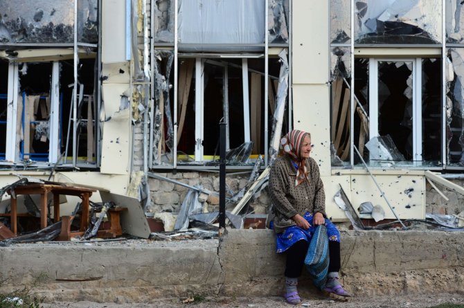 AFP/„Scanpix“ nuotr./Pagyvenusi moteris šalia nuniokoto pastato