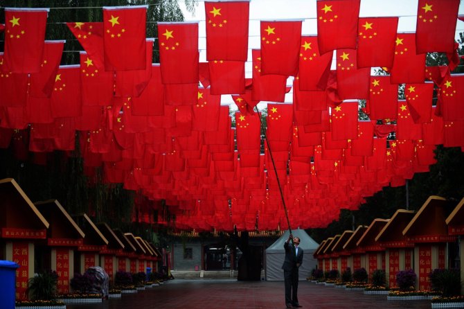 AFP/„Scanpix“ nuotr./Vyras taiso Kinijos vėliavą prieš nacionalinę šventę
