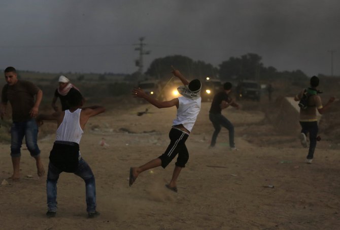 AFP/„Scanpix“ nuotr./Palestiniečiai mėto akmenis į Izraelio pareigūnus.