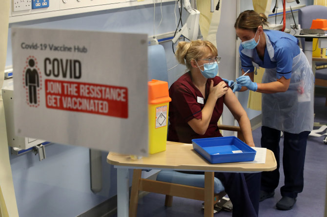AFP/„Scanpix“ nuotr./Jungtinėje Karalystėje žmonės skiepijasi nuo koronaviruso