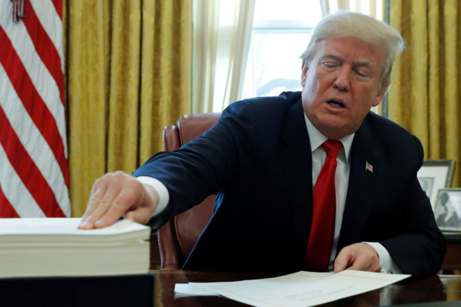 „Reuters“/„Scanpix“ nuotr./Donaldas Trumpas pasirašo įstatymą dėl mokesčių reformos