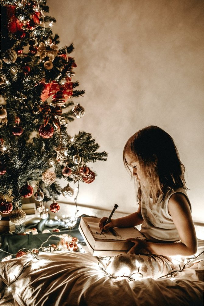 Jonathan Borba / Unsplash nuotr./Mergaitė rašo laišką Kalėdų Seneliui