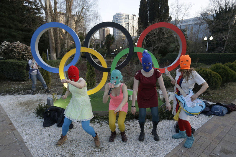 Members of the punk group Pussy Riot, including Nadezhda Tolokonnikova in the aqua balaclava, center, and Maria Alekhina in the red balaclava, left, perform next to the Olympic rings in Sochi, Russia, on Wednesday, Feb. 19, 2014. Cossack militia attacked the punk group with horsewhips earlier in the