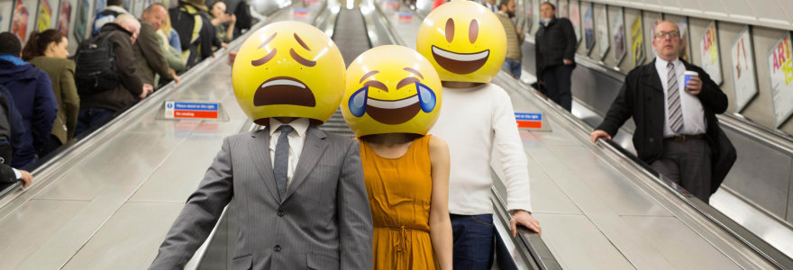 Žmonės su emoji šypsenėlių kaukėmis