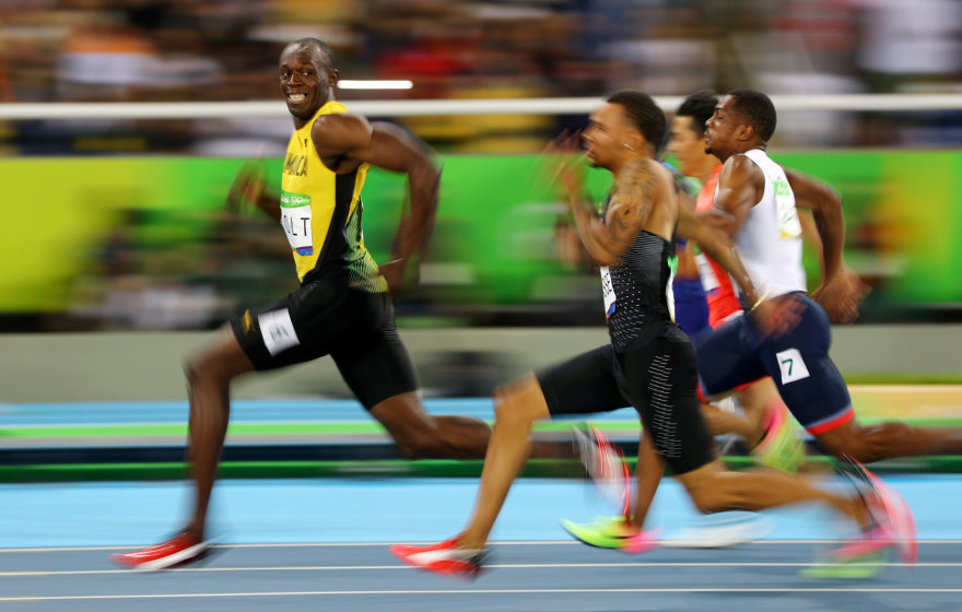 „Reuters“/„Scanpix“ nuotr./Brazilija, 2016 rugpjūčio 14 d. Olimpinėje 100 m bėgimo rungtyje Usainas Boltas žvilgteli į nuo jo atsiliekančius bėgikus